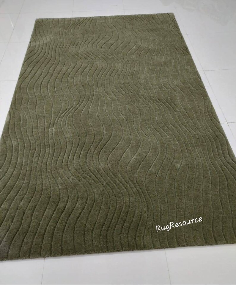 May include: A green area rug with a wavy, textured pattern. The rug has a subtle sheen and is made of a soft, plush material. The text "RugResource" is visible in the bottom right corner of the rug.