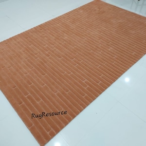May include: A close-up of a light orange rug with a textured, striped pattern. The rug is made of a soft, plush material and has a subtle sheen.