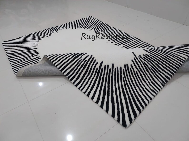 May include: A white and black striped rug with a circular design in the center. The rug is rolled up and the underside is visible.