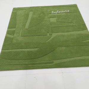May include: A green area rug with a modern abstract design. The rug has a raised texture and is made of a soft, plush material.