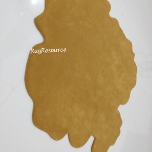 May include: A large, brown, irregularly shaped rug with a soft, fuzzy texture. The rug is made of a plush material and has a unique, organic shape. The text "RugResource" is visible in the lower left corner of the rug.