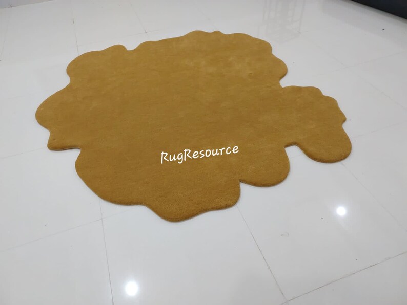 May include: A large, mustard yellow, fluffy, irregularly shaped rug. The rug is made of a soft, plush material and has a unique, organic shape.