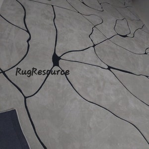 Puede incluir: Una alfombra gris y negra con un dise&ntilde;o abstracto moderno. La alfombra presenta una red de l&iacute;neas negras que se asemejan a venas o ramas, creando un aspecto &uacute;nico y contempor&aacute;neo.