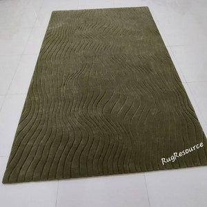 May include: A green area rug with a wavy, textured pattern. The rug has a subtle sheen and is made of a soft, plush material.