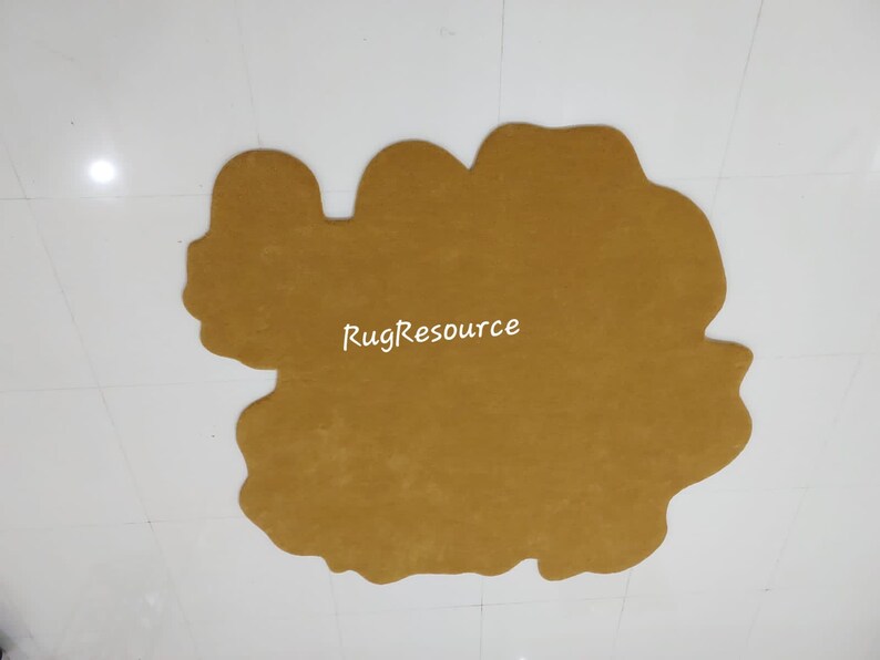 May include: A large, mustard yellow, irregularly shaped rug with a slightly fuzzy texture. The rug is on a white tiled floor. The text "RugResource" is printed in white on the rug.