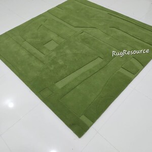 May include: A green, abstract patterned rug with a raised texture. The rug is made of a soft, plush material. RugResource is printed in white on the rug.