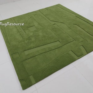 May include: A green area rug with a geometric design. The rug has a raised texture and is made of a soft, plush material.