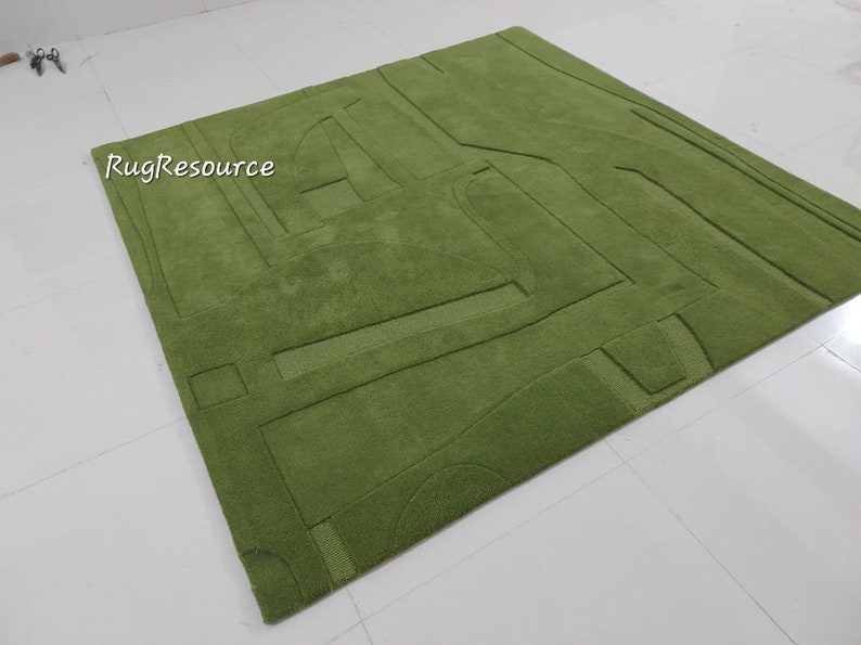 May include: A green area rug with a geometric design. The rug has a raised texture and is made of a soft, plush material.