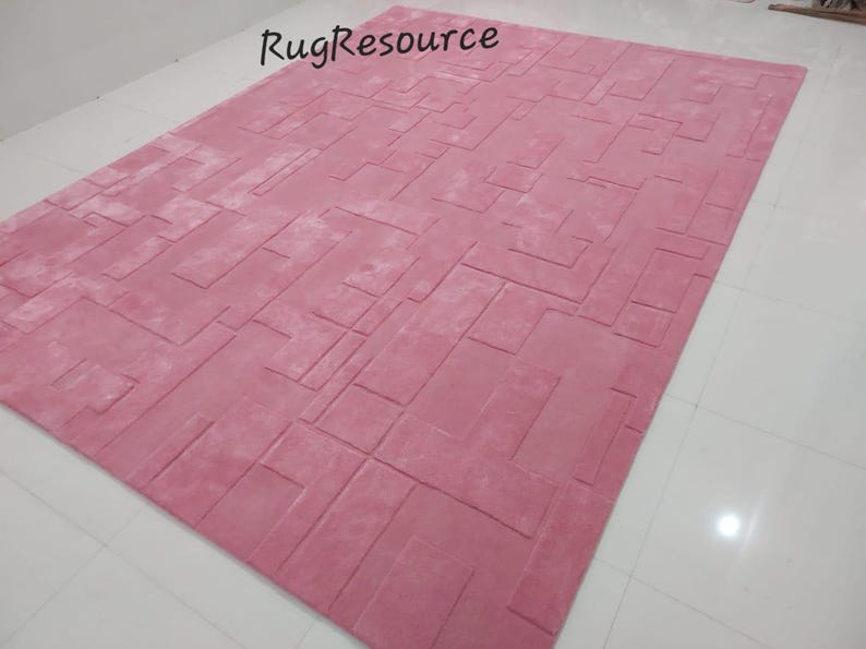 May include: A pink area rug with a geometric pattern. The rug has a soft, plush texture and is perfect for adding a touch of color and style to any room.