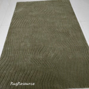 May include: A green area rug with a wavy, textured pattern. The rug is made of a soft, plush material.