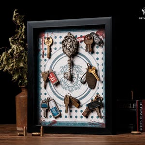 May include: A framed display featuring antique keys of various shapes and sizes, arranged on a patterned background. The keys are in shades of gold, silver, and bronze. The frame is black, and the text "Grim Reliquary" is visible.