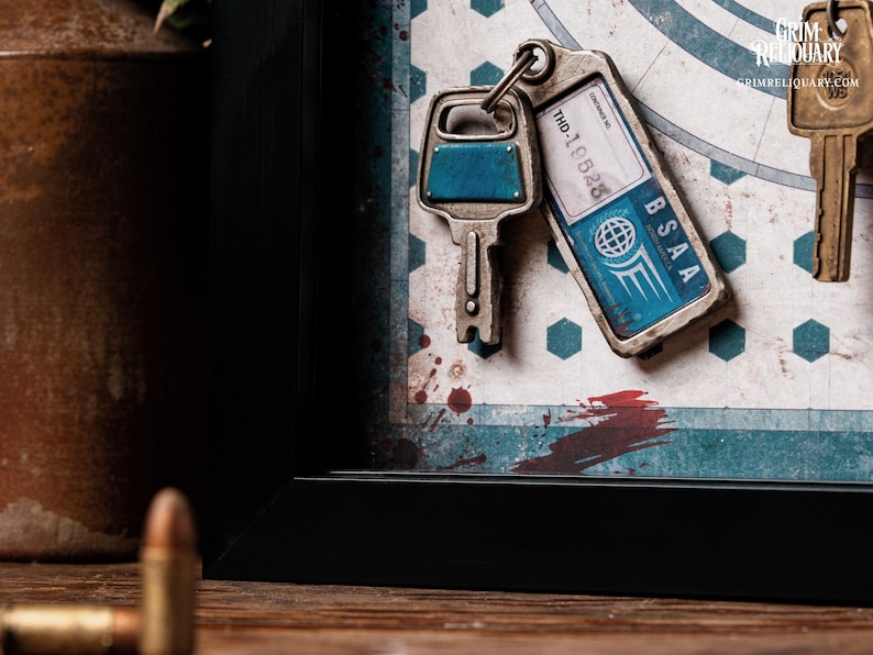 May include: A framed artwork featuring three keys. One key has a blue accent, and another has a tag that reads "BSAA" and "THD-19528." The background has a map design with red and blue accents. The artwork is in a black frame.
