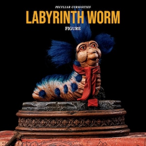 May include: A detailed figure of the Labyrinth Worm, featuring a tan body with blue spots and a red scarf. The worm has blue, fluffy hair and is displayed on a decorative base with the text "LABYRINTH WORM FIGURE".