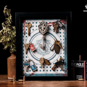 May include: A framed display featuring various antique keys and keychains. The keys are arranged on a patterned background with a central decorative key. A box of Red Eagle brand ammunition is visible.