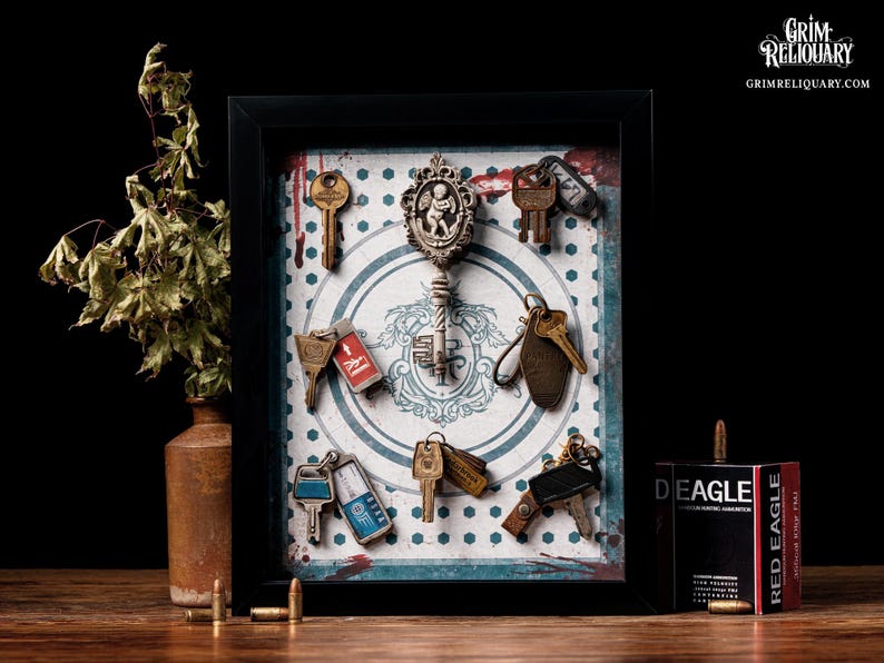 May include: A framed display featuring various antique keys and keychains. The keys are arranged on a patterned background with a central decorative key. A box of Red Eagle brand ammunition is visible.
