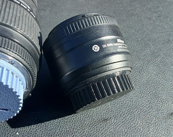 May include: Two black camera lenses with a blue lens cap on one of the lenses.