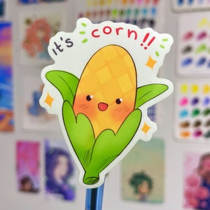 May include: A cute cartoon corn on the cob with a smiling face and green husks. The text "It's corn!!" is written above the corn.