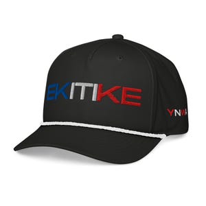 Op de afbeelding: Zwarte baseballcap met het geborduurde woord "EKITIKE" in blauw, wit en rood. De cap heeft een wit touwdetail en de letters "YNWA" zijn rood op de zijkant geborduurd.
