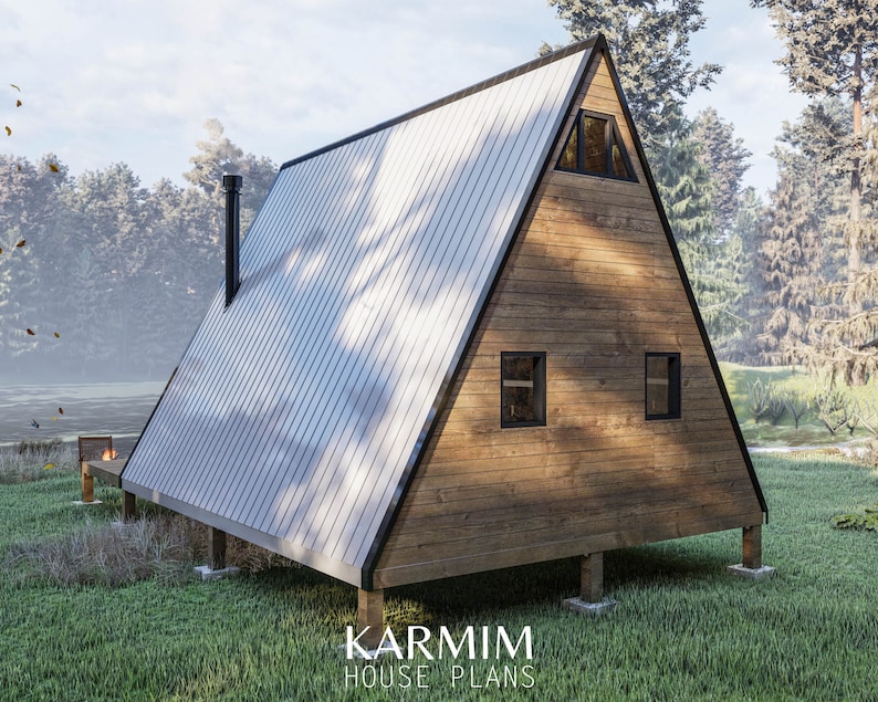 May include: A wooden A-frame cabin with a metal roof, two windows, and a chimney. The cabin is on stilts and surrounded by green grass.
