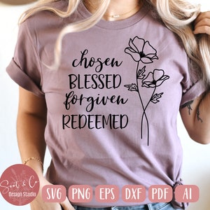 Könnte beinhalten: Ein lila T-Shirt mit dem Text "chosen blessed forgiven redeemed" in schwarzer Schrift. Das Shirt zeigt außerdem eine schwarze Linienzeichnung von zwei Blumen.
