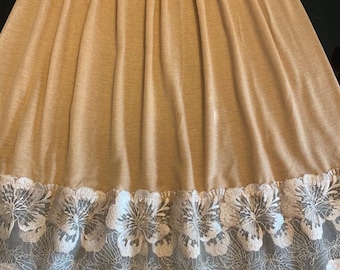 May include: A beige slip skirt with a white floral lace trim. The skirt is made of a soft, stretchy fabric and has an elastic waistband.