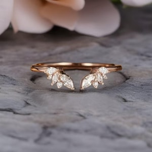 Op de afbeelding: Een ring van roségoud met een gesplitst bandontwerp. De band is versierd met marquise- en ronde diamanten, wat een delicate en elegante uitstraling creëert.