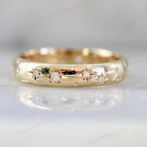 Peut inclure: Une bague dorée avec un motif céleste. La bague présente de petites pierres précieuses scintillantes serties dans des motifs en forme d'étoile. La bague est probablement en or. Il s'agit d'un bijou.