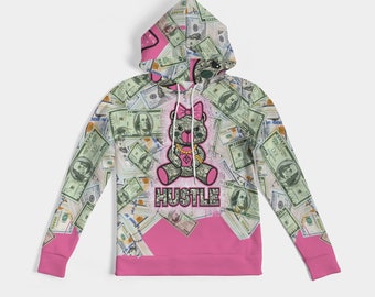 May include: Pink hoodie with a money print featuring a cartoon bear with a pink bow and the word "Hustle" in black letters.