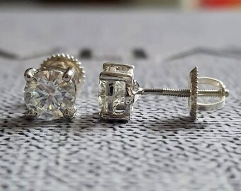 May include: A pair of silver stud earrings with round, clear gemstones. The earrings have a screw-back closure.