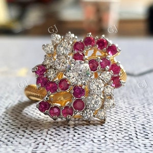 Puede incluir: Un anillo de oro con un diseño de espiral adornado con rubíes rojos y diamantes blancos.