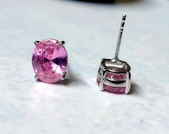 May include: A pair of silver stud earrings with pink oval-shaped gemstones.