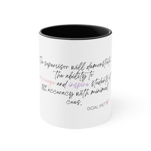 Puede incluir: Taza de café de cerámica blanca con borde negro. La taza presenta una cita escrita a mano que dice: "The supervisor will demonstrate the ability to encourage and inspire students at 100% accuracy with minimal cues. GOAL MET." La cita está escrita en tinta negra con las palabras "encourage" y "GOAL MET" en tinta rosa y morada.