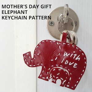 Peut inclure: Porte-clés en forme d'éléphant en cuir rouge avec des coutures blanches et les mots "With Love" brodés sur le côté.