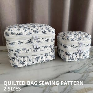 Puede incluir: Dos bolsas acolchadas con un estampado floral en blanco y gris. Las bolsas tienen cremalleras blancas y están disponibles en dos tamaños. El texto en la parte inferior dice "QUILTED BAG SEWING PATTERN" y "2 SIZES".