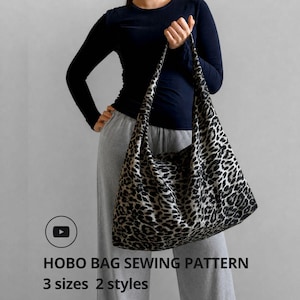 May include: A large hobo bag with a black and tan leopard print pattern. The bag is held by a person wearing a navy blue long-sleeve shirt and gray sweatpants. The image includes the text "HOBO BAG SEWING PATTERN 3 sizes 2 styles."