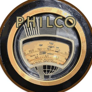 May include: A vintage Philco radio dial with a black and gold circular design. The dial features a cream-colored face with a tuning scale, station indicators, and the text "PHILCO". The dial is surrounded by a black and gold frame.