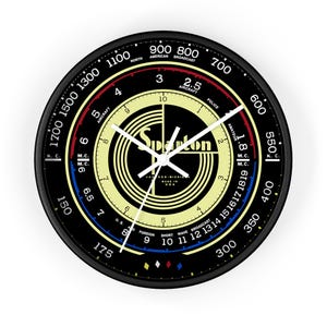 May include: A black and white clock with a yellow center and a white dial. The clock face has a black and white logo with the word "Spartan" in the center. The clock face also has numbers and markings for different radio frequencies. The clock is 12 inches in diameter.