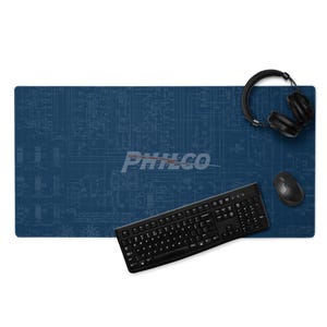May include: A blue desk mat with a blueprint design, a black keyboard, a black mouse, and black headphones. The mat has the word "PHILCO" printed on it.
