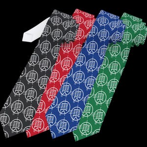 May include: Five neckties in black, red, blue, and green, each with a white geometric pattern. The ties are arranged diagonally against a black background, with the white tie tips visible.