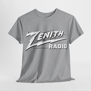 May include: A gray t-shirt with the words "ZENITH RADIO" in a white, retro-style font. The text "LONG DISTANCE" is below the "ZENITH" text. The shirt has short sleeves and a crew neck.