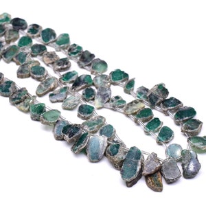 May include: A strand of green gemstone beads, each bead is a unique, irregular shape with a rough, natural texture.