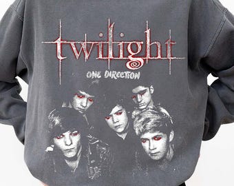 May include: Gray sweatshirt with the text "twilight ONE DIRECTION" in red. The sweatshirt features a graphic of five people. The model is wearing black shorts and a white undershirt.