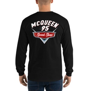 Könnte beinhalten: Schwarzes Langarmshirt mit Grafik auf dem Rücken. Die Grafik zeigt den Text "McQueen 95 Speed Shop" in Weiß und Rot, mit einem stilisierten Emblem. Das Shirt ist aus einem weichen Material.