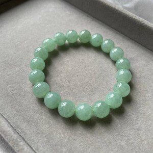 May include: A jade green beaded bracelet with round beads. The bracelet is in a gray velvet box.