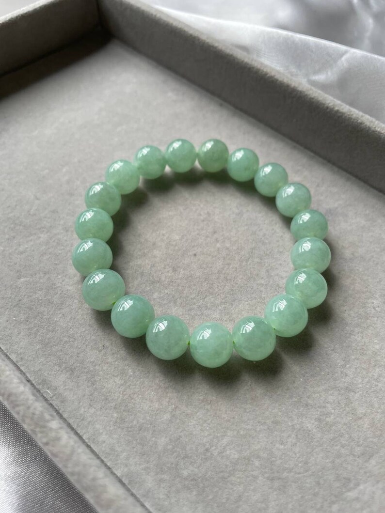 May include: A jade green beaded bracelet with round beads. The bracelet is in a gray velvet box.