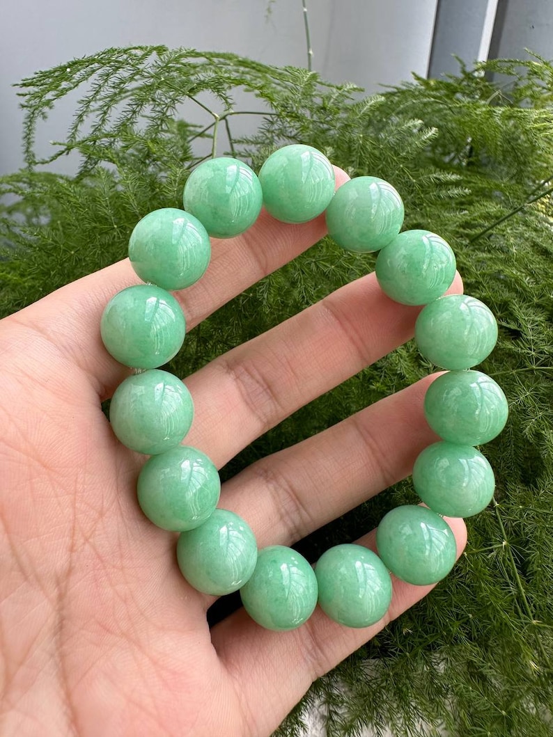 K&ouml;nnte beinhalten: Ein Jade-Armband aus runden Perlen. Das Armband ist aus nat&uuml;rlichem Jade und hat eine sch&ouml;ne gr&uuml;ne Farbe.