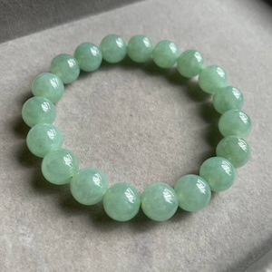 May include: A jade green beaded bracelet with round beads. The bracelet is made of natural jade and has a smooth, polished finish.