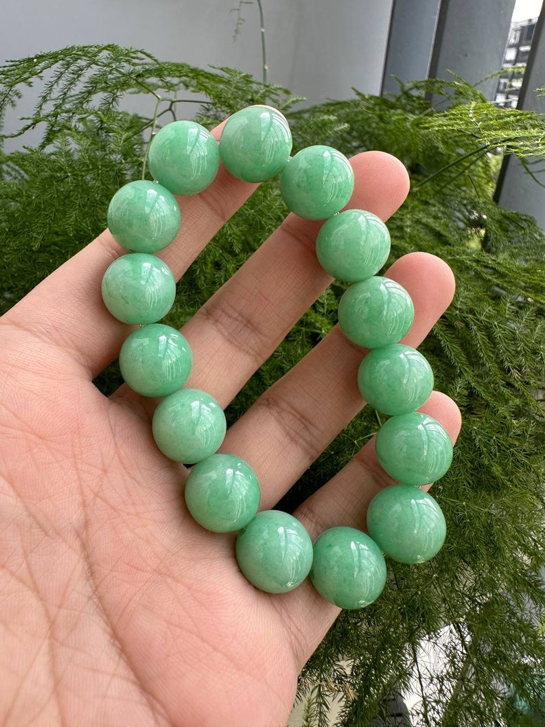 K&ouml;nnte beinhalten: Ein Jade-Armband aus runden Perlen. Das Armband ist aus nat&uuml;rlichem Jade und hat eine sch&ouml;ne gr&uuml;ne Farbe.