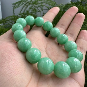 K&ouml;nnte beinhalten: Ein Armband aus Jadegr&uuml;n mit runden Perlen. Das Armband ist aus nat&uuml;rlichem Jade gefertigt und hat eine glatte, polierte Oberfl&auml;che.