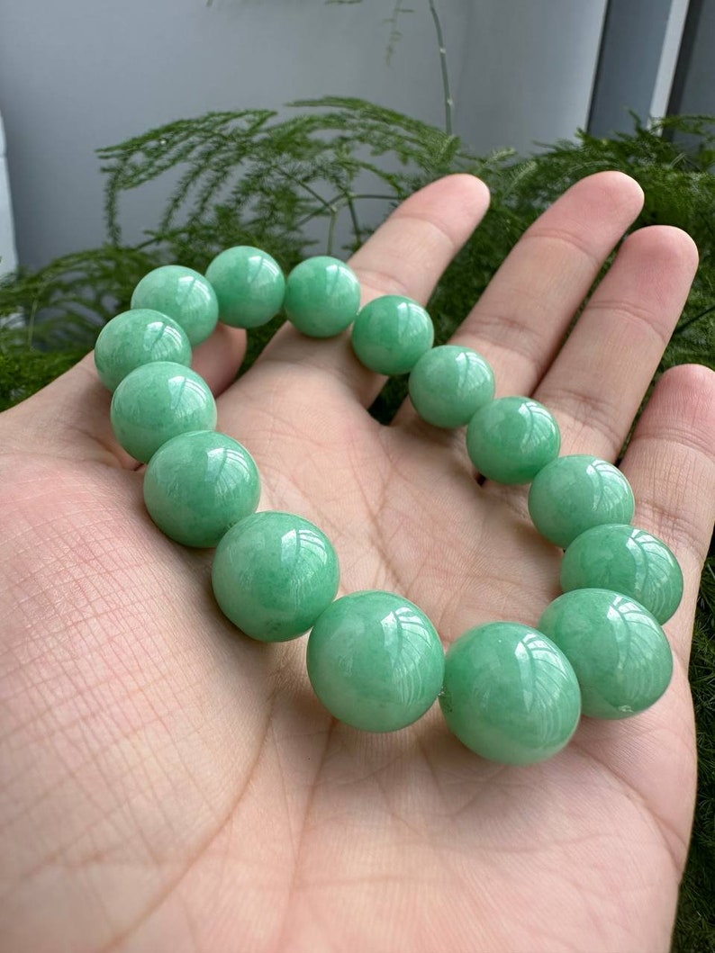 K&ouml;nnte beinhalten: Ein Armband aus Jadegr&uuml;n mit runden Perlen. Das Armband ist aus nat&uuml;rlichem Jade gefertigt und hat eine glatte, polierte Oberfl&auml;che.
